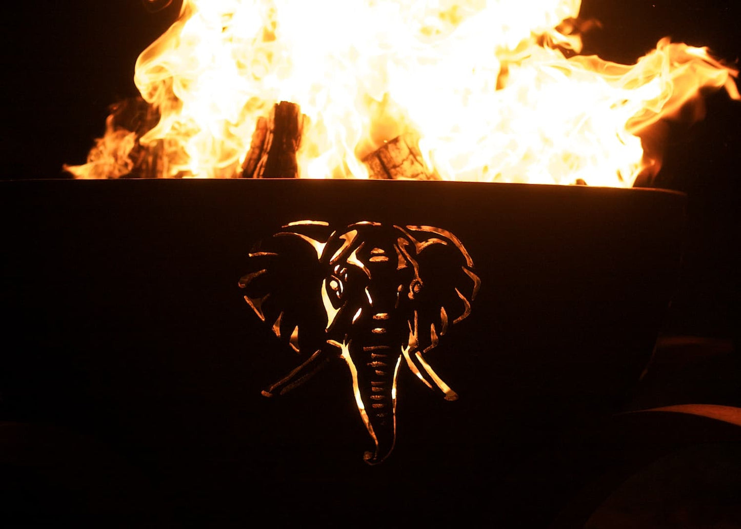 Elephant cutout glowing from inside the lit Africa’s Big Five fire pit at night.
