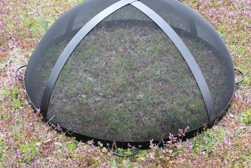 40” black heavy stainless steel mesh Spark Guard with two-inch wide 304 stainless steel bands sitting by itself on the grass. Fits Fire Pit Art style: Nepal (sold separately).