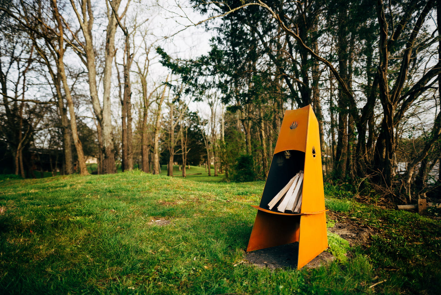 Orange camping tent in a grassy area with trees in the background