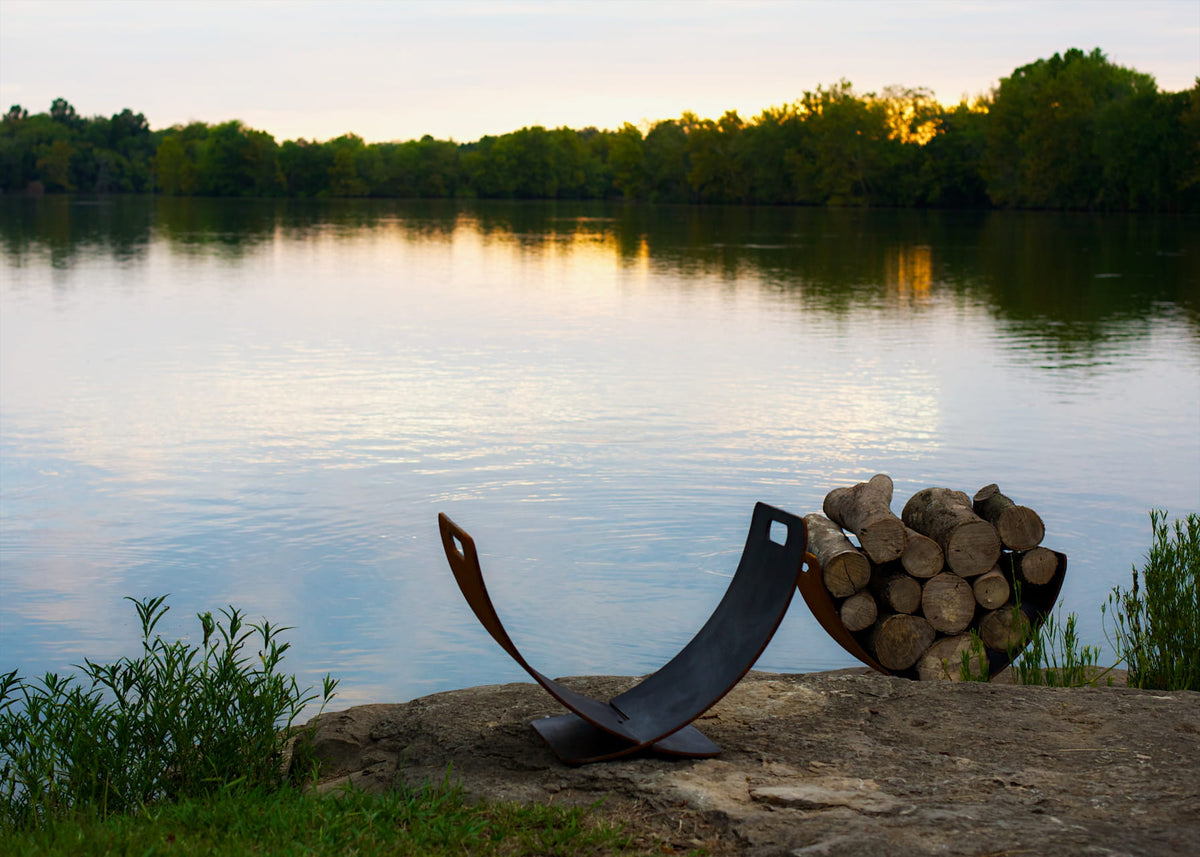 View of two carbon steel Wings in Flight log racks side by side. One is empty and the other is filled with wood. By Fire Pit Art.