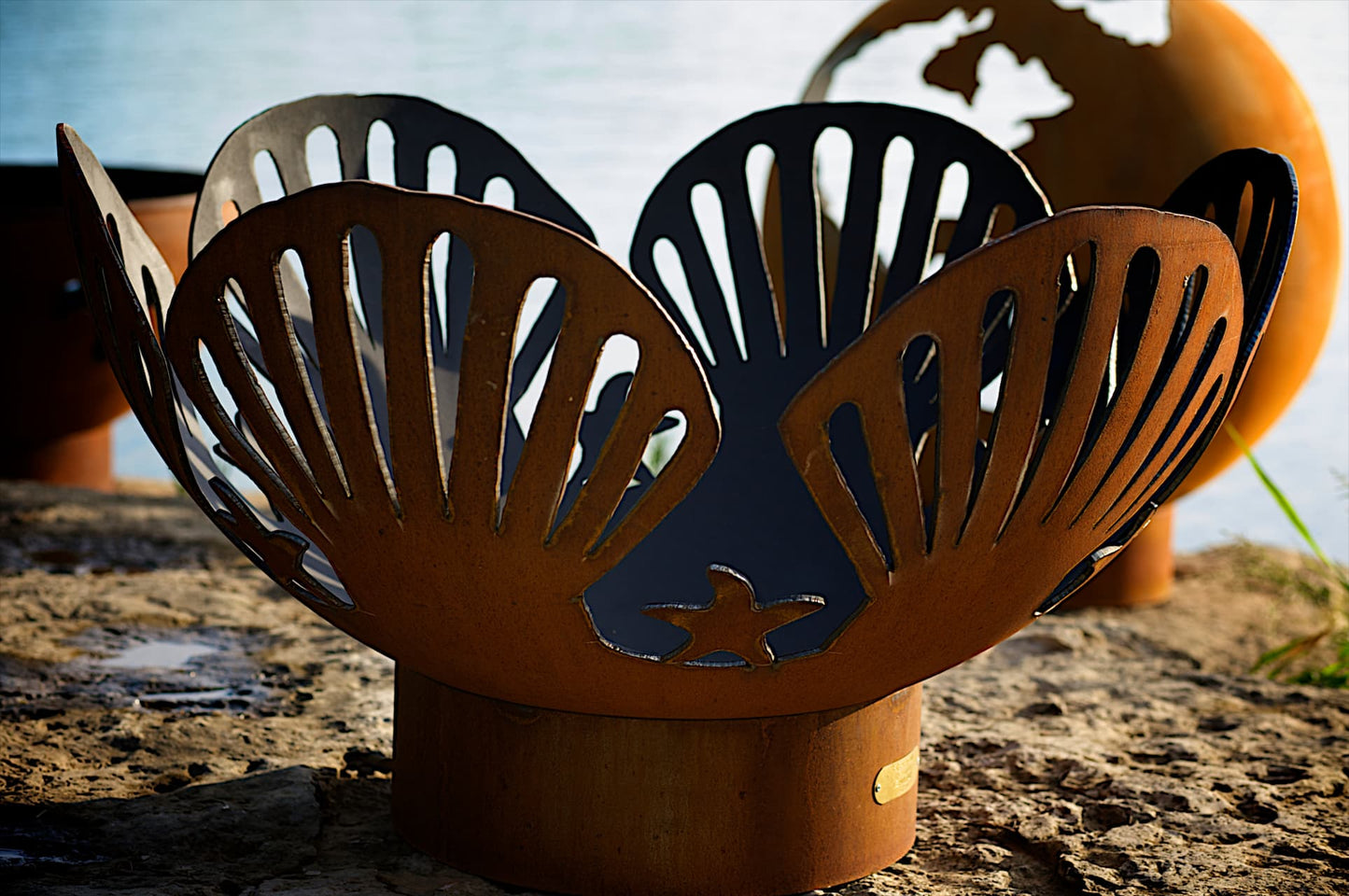 Close-up of shell cutouts and starfish on Barefoot Beach 42" Carbon Steel Fire Pit by Fire Pit Art.