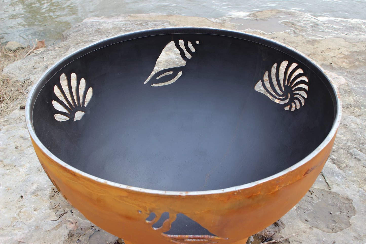 Inside view of the Beachcomber 36" steel fire pit showing detailed shell and starfish cutouts. Made in USA.