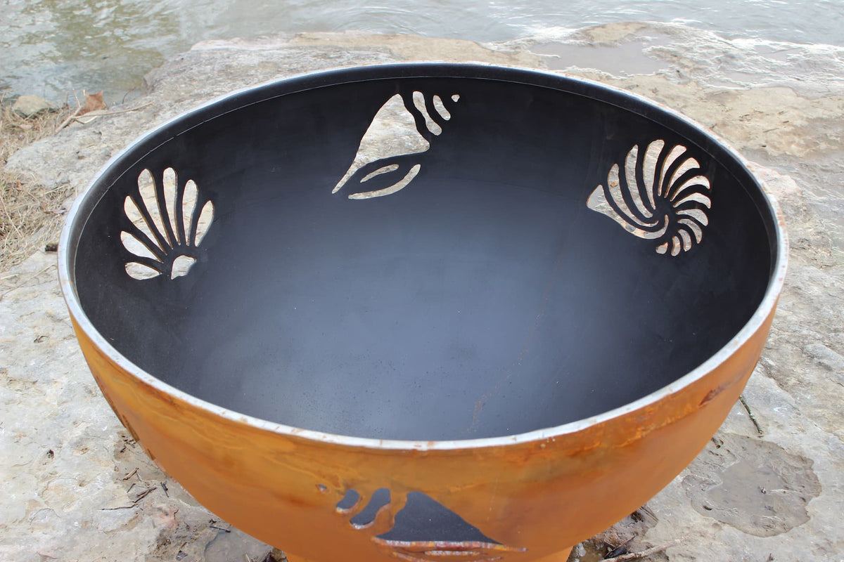 Inside view of the Beachcomber 36" steel fire pit showing detailed shell and starfish cutouts. Made in USA.