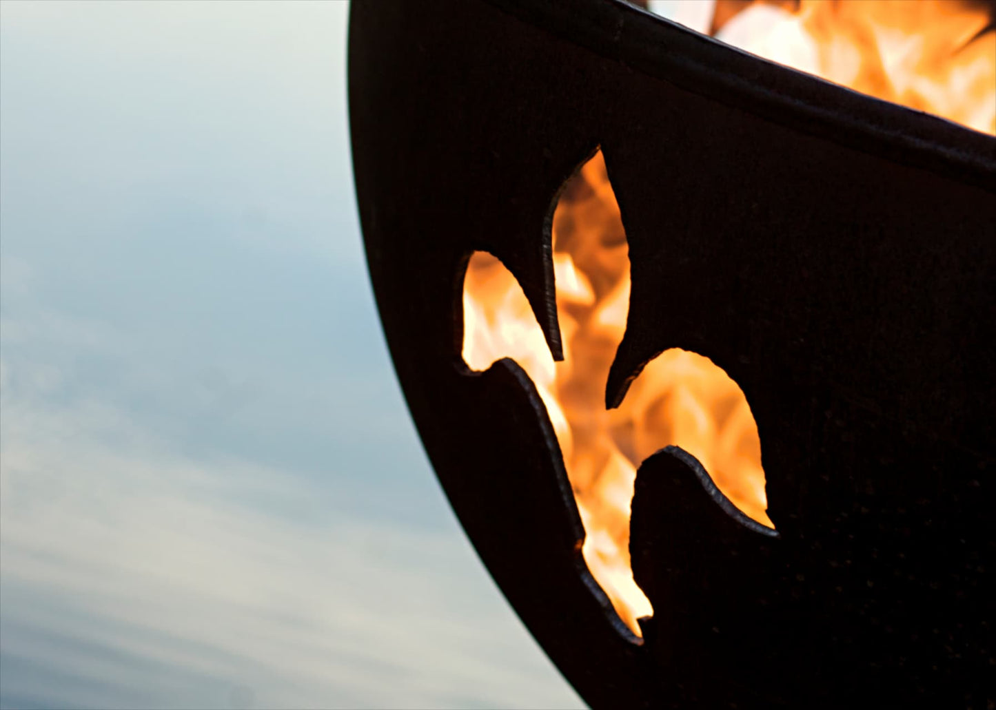 Detailed closeup of Fire Pit Art's Fleur de Lis flame pattern dancing through precision-cut design on fire pit.