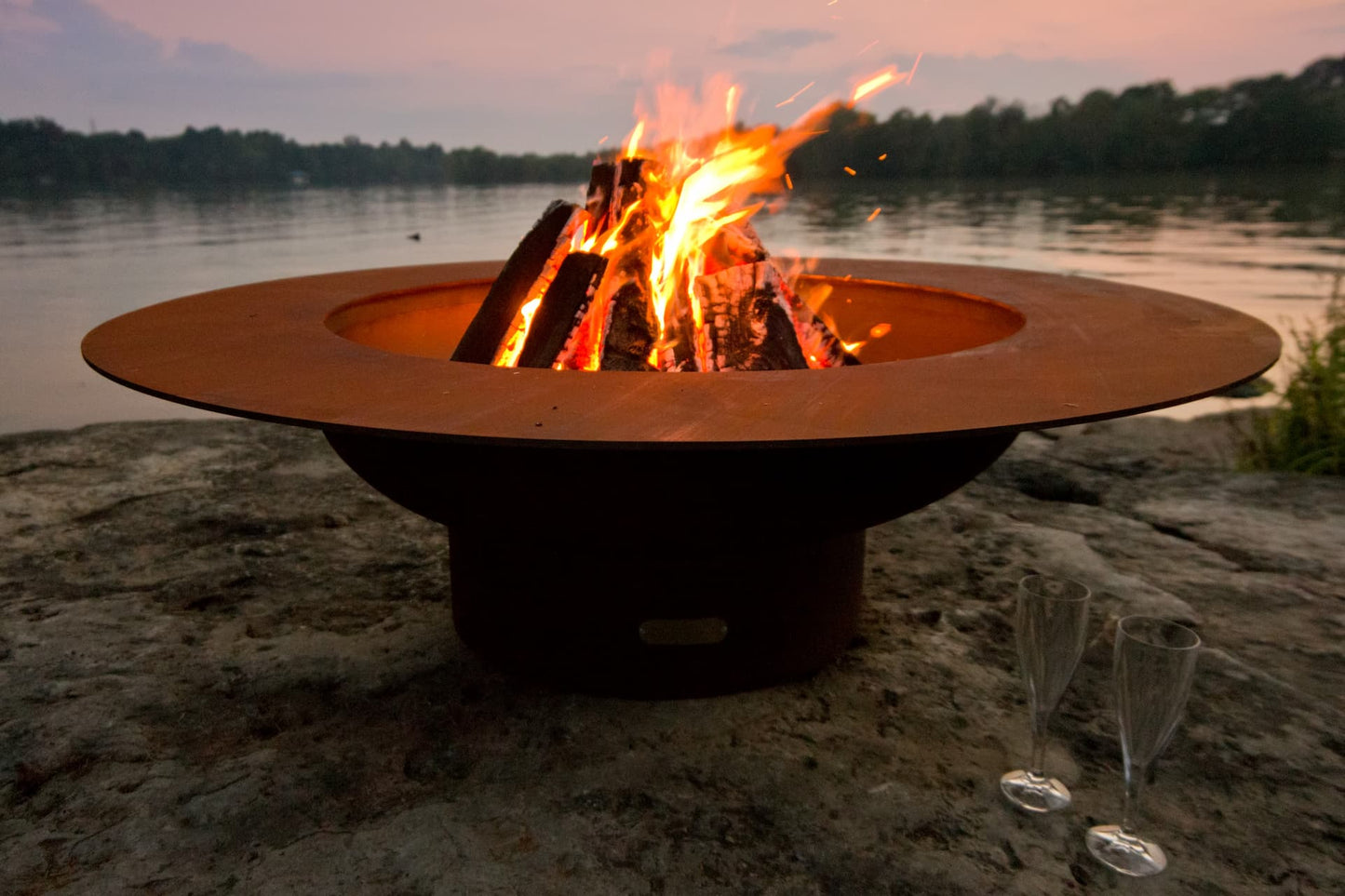 Magnum 54" carbon steel fire pit with tall flames during golden hour. Made in USA by Fire Pit Art.
