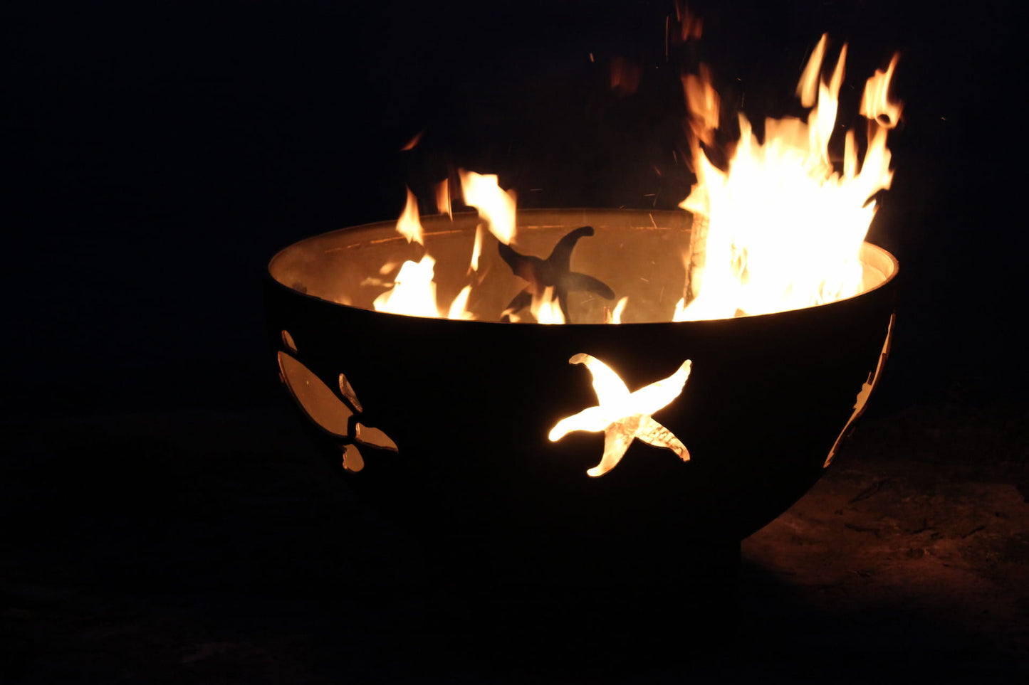 Overhead view of Sea Creatures fire pit with large flames and glowing cutout shapes. Made in USA by Fire Pit Art.