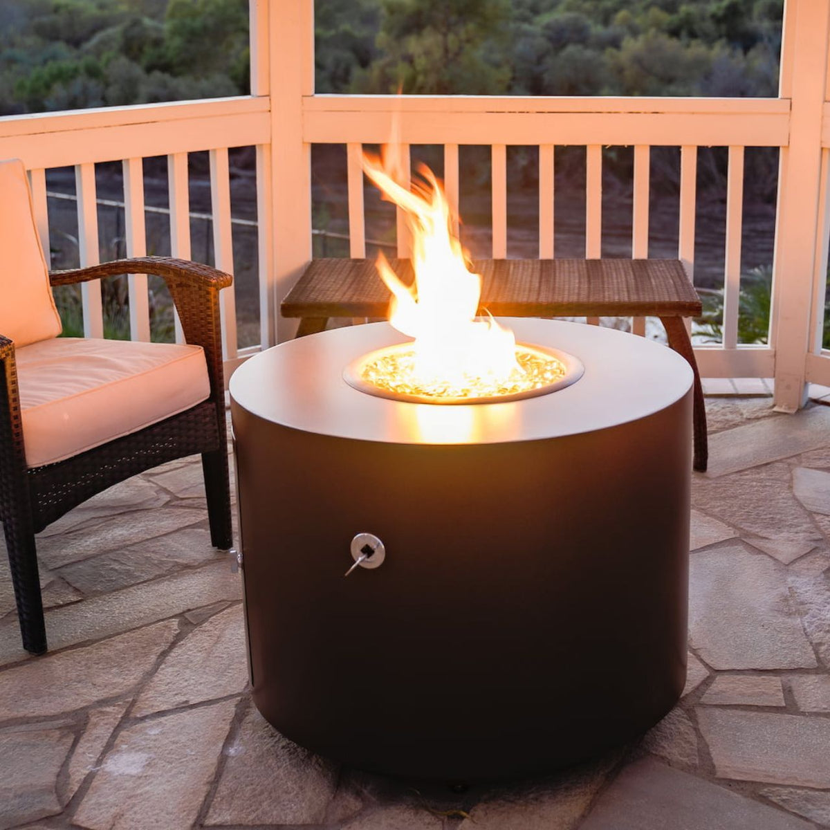The lit Beverly round steel fire pit in copper vein powder coat on a patio.
