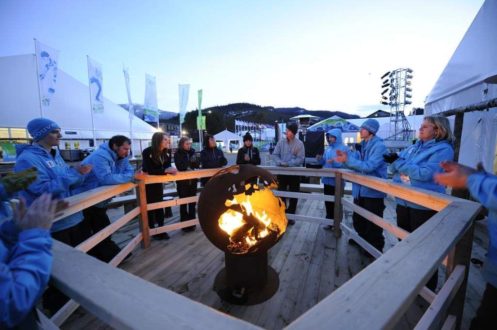 Group of people gathered around the Third Rock 36" carbon steel fire pit.