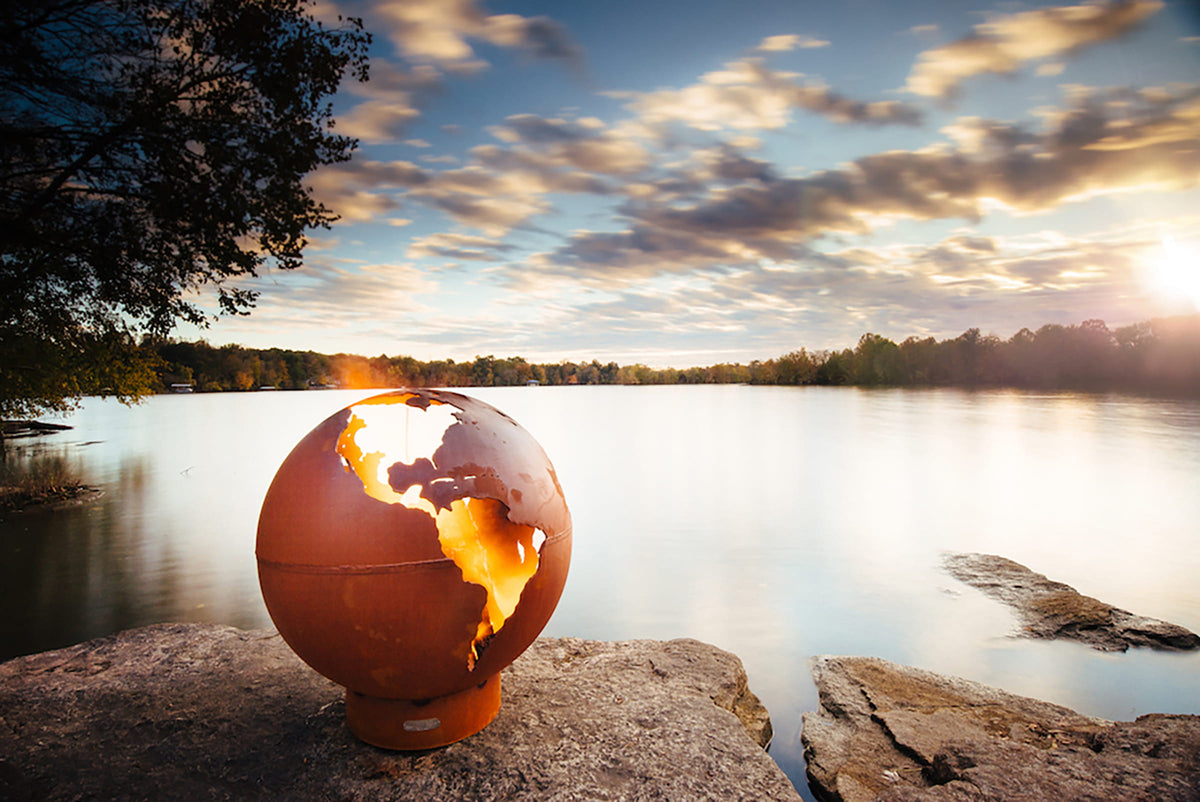 Third Rock 36-inch fire pit glowing at dusk with a panoramic view of the lake in the background.