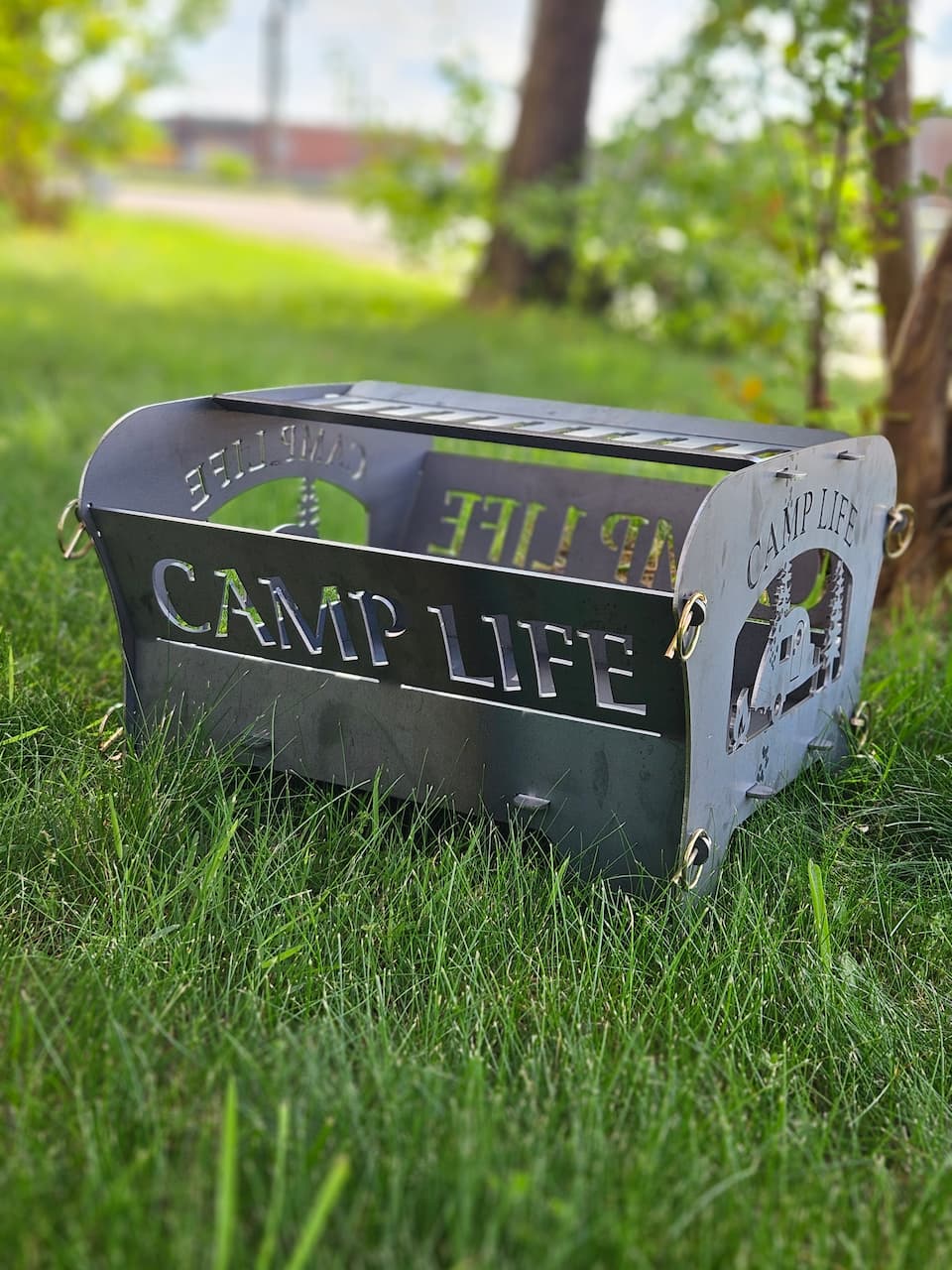 Side view of Camp Life collapsible wood burning fire pit on grassy lawn.