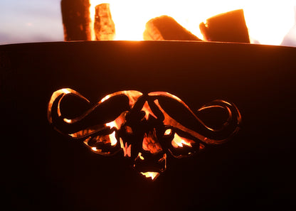 Night fire in carbon steel fire pit highlighting glowing Cape Buffalo silhouette.