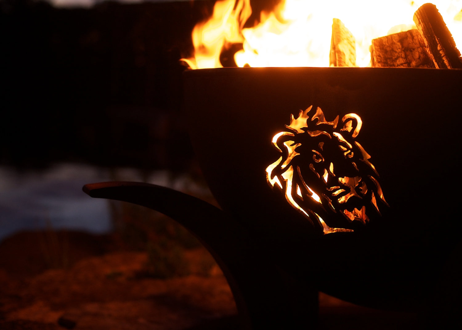 Night fire in Africa's Big Five carbon steel fire pit with glowing lion silhouette.
