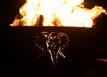 Elephant cutout glowing from inside the lit Africa’s Big Five fire pit at night.