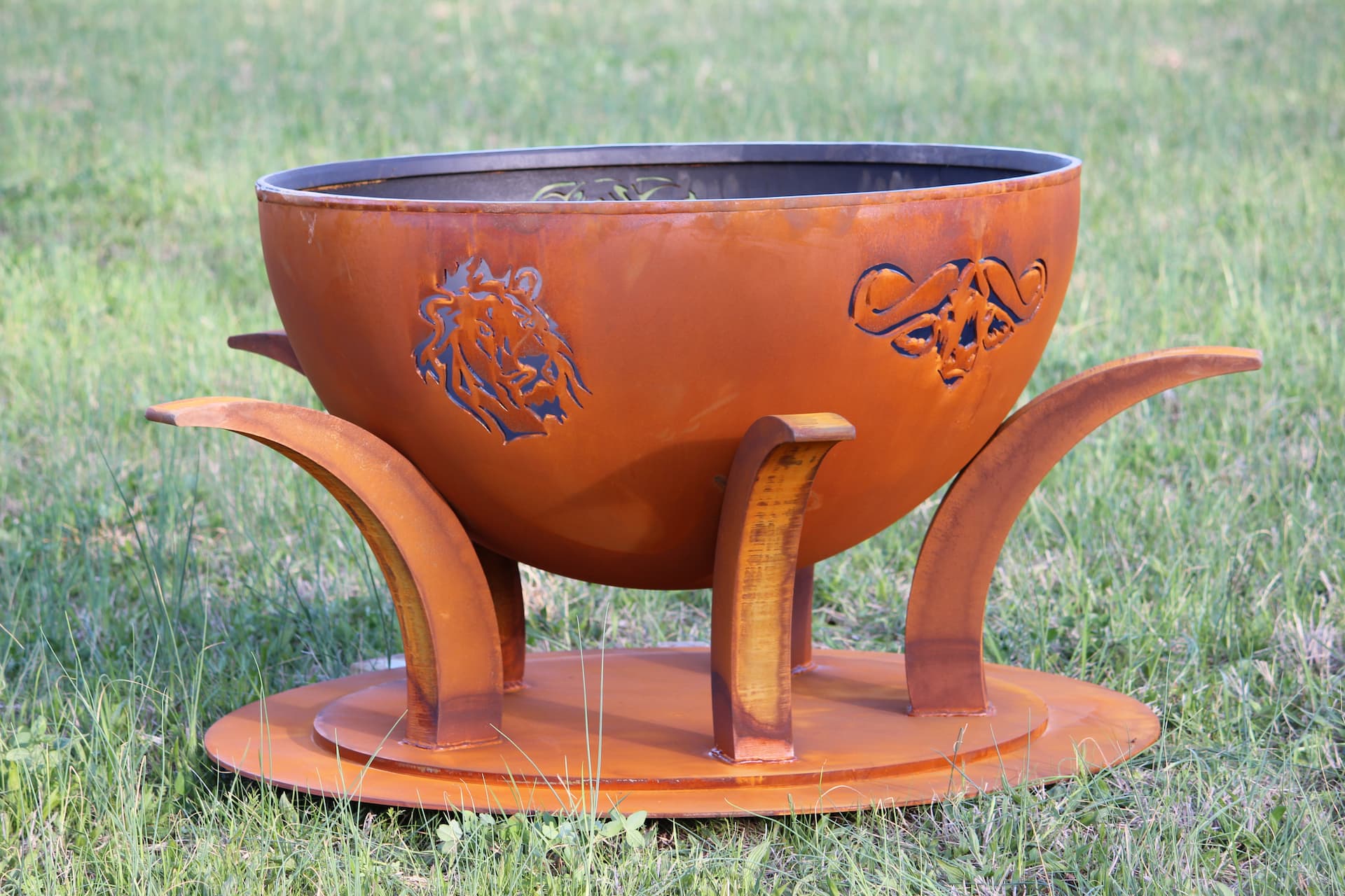 Side view of Africa’s Big Five fire pit with animal designs, unlit in outdoor setting. By Fire Pit Art.