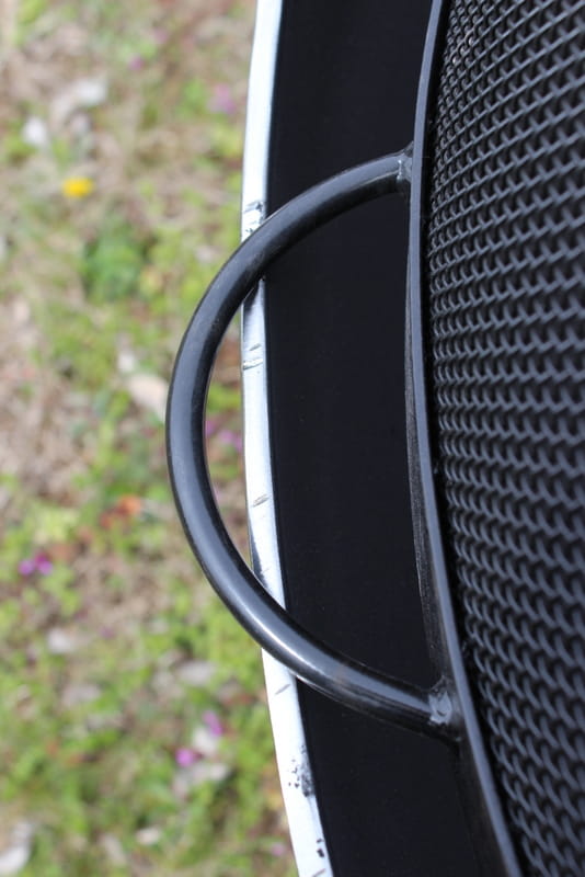 Close-up of steel carrying handle on the side of 40” black heavy stainless steel mesh Spark Guard by Fire Pit Art (fits Nepal only, sold separately).
