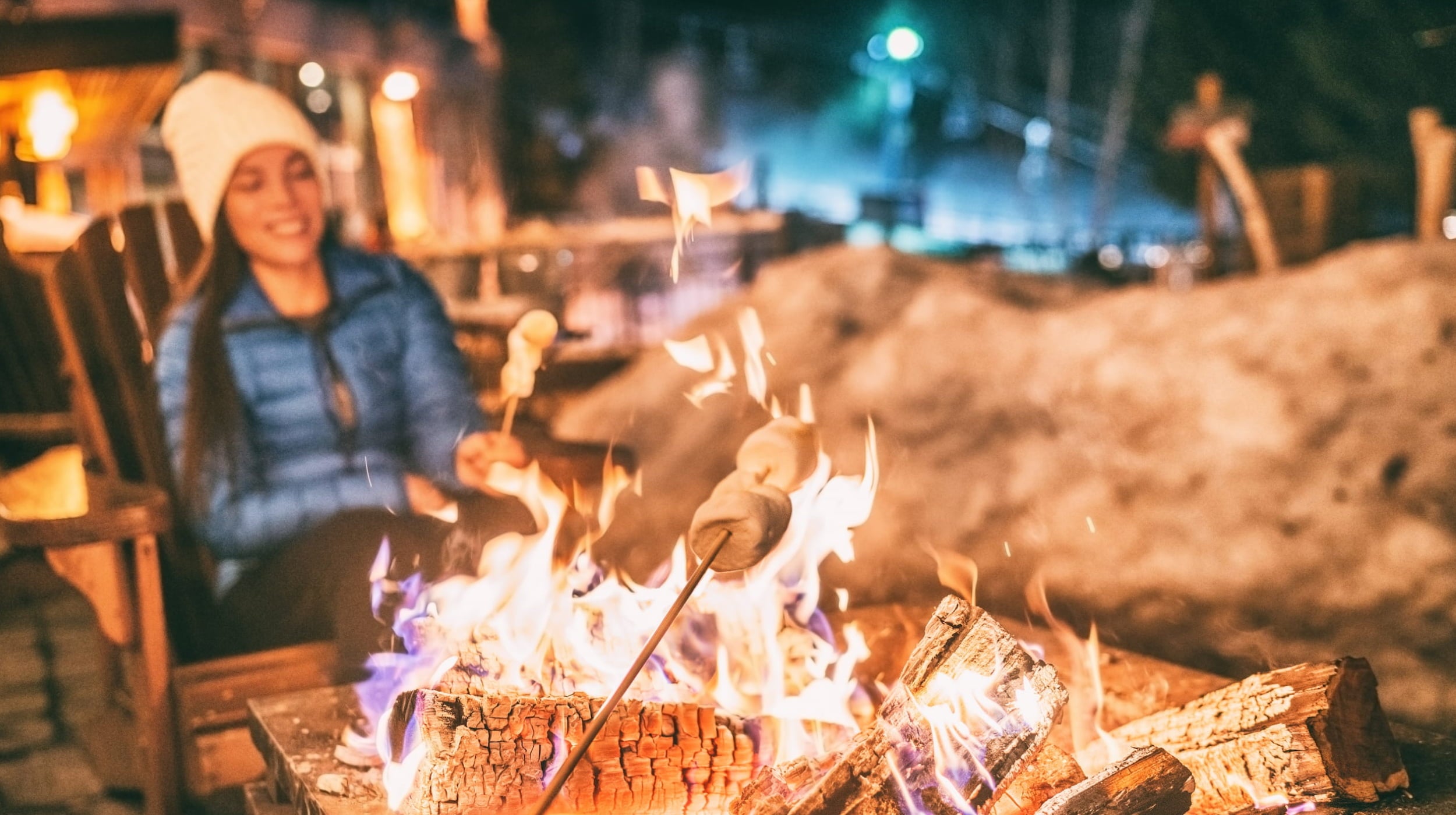 Person roasting marshmallows over a campfire at night.
