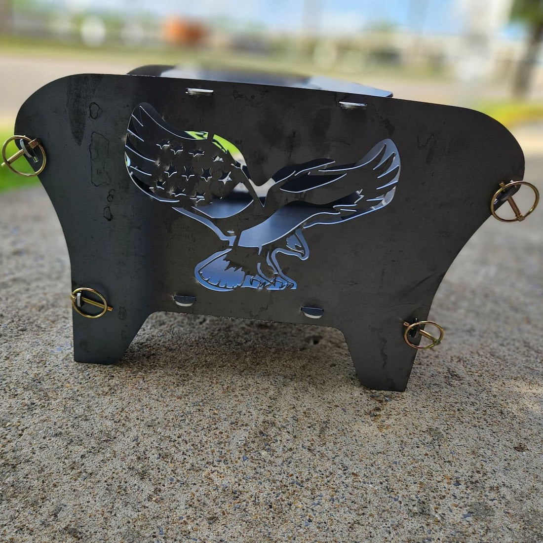 A collapsible metal fire pit with an eagle cut-out design, featuring &