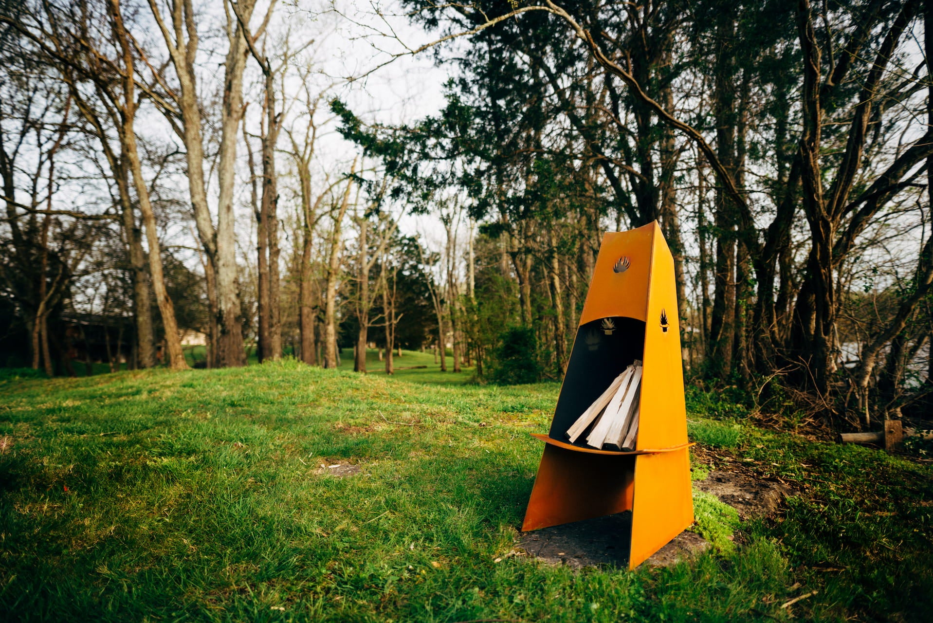 Orange camping tent in a grassy area with trees in the background