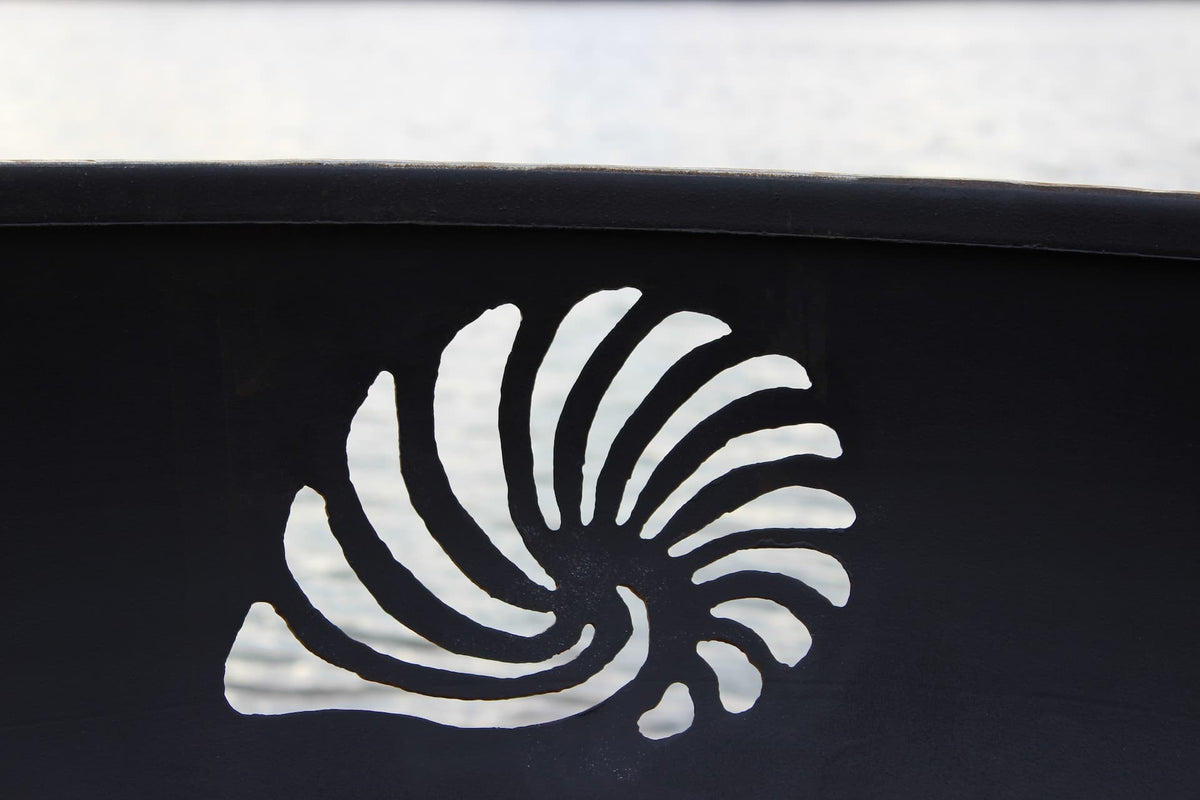Close-up of seashell design cut into the Beachcomber 36" steel fire pit side. Made in the USA.