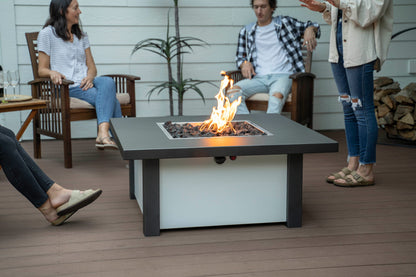 People chatting on patio around Carolina Evening Companion Square fire table lit with gentle flame (shown in Endura Charcoal & White).