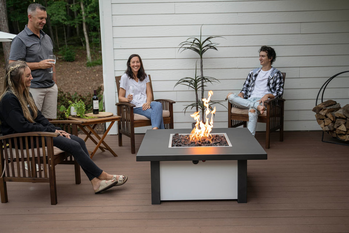 Group of friends gathered around lit Carolina Evening Companion Square fire table enjoying wine and conversation outdoors (table shown in Endura Charcoal and White).
