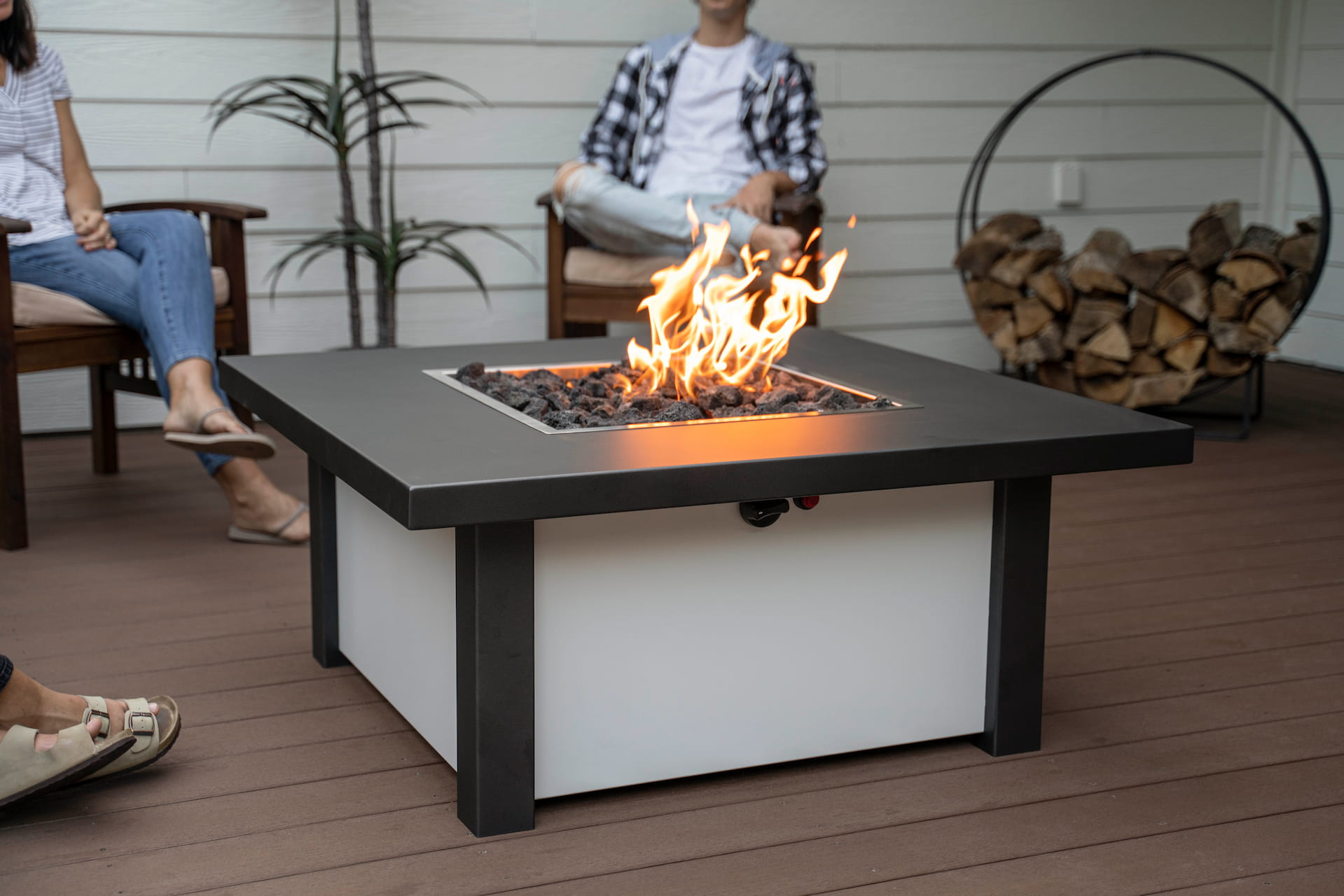 Close up of lit Carolina Evening Companion Square fire table in use during evening gathering, fire glowing warmly on patio (shown in Endura Charcoal and White).