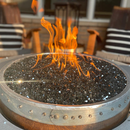 Close-up of fire glass in wine barrel fire pit – sparkling black glass reflecting firelight (fire glass sold separately).
