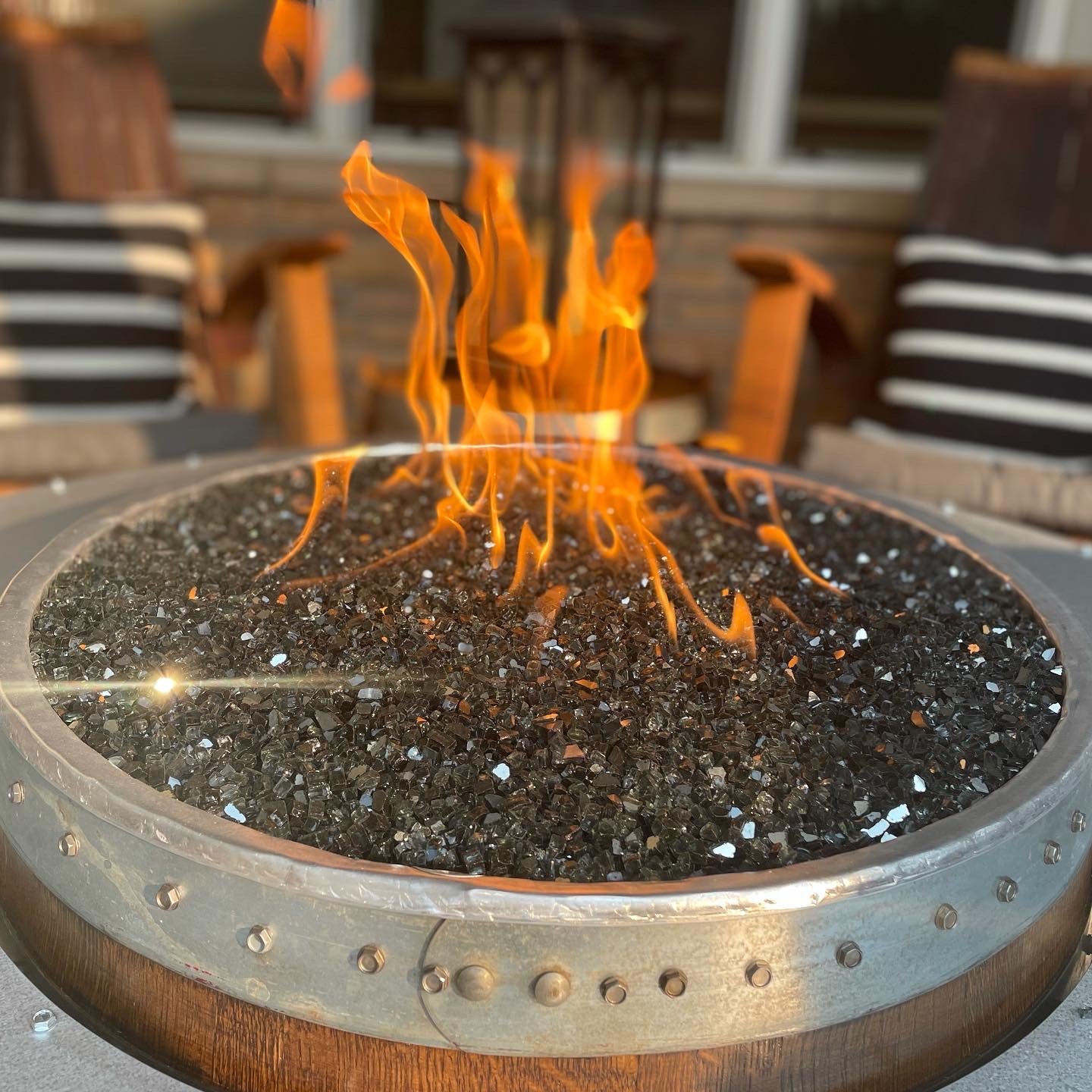 Wine Barrel Fire Pit burning with black reflective fire glass glowing under flame.