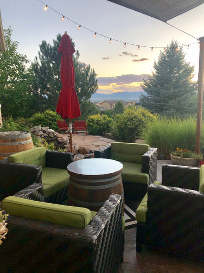 Wine barrel coffee table with matching lid on an outdoor patio at sunset with wicker seating and mountain view.