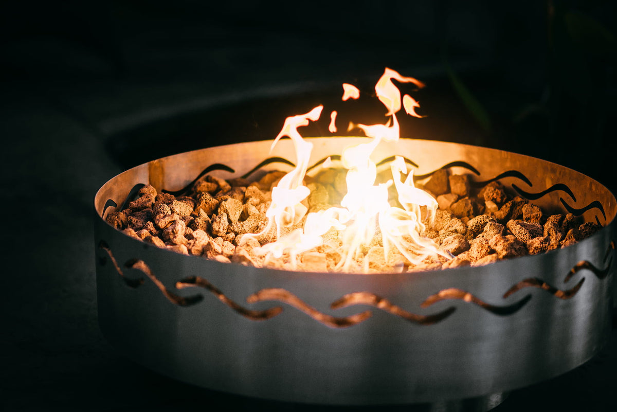 Close up view of Fire Surfer steel fire pit showing flame and lava rocks.