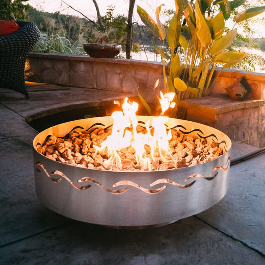 Fire Surfer steel fire pit with bright flame on patio at sunset.  Made in the USA by Fire Pit Art.