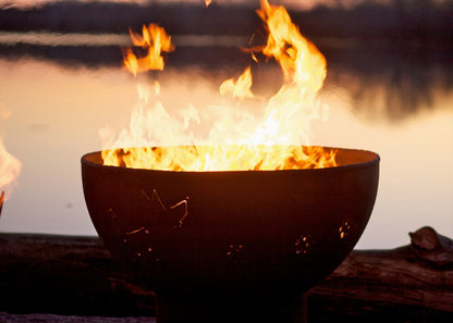 Side profile of Funky Dog 36" carbon steel fire pit featuring metal dog cutouts and even flames with twilight sky.