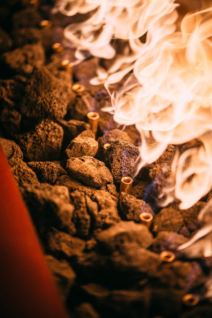 Close-up view of bright orange flames and lava rock in the Linear fire pit table.