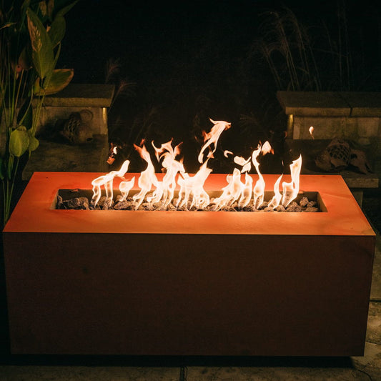 Rectangular steel Linear fire pit table glowing with warm flames at night.  Made in the USA by Fire Pit Art.