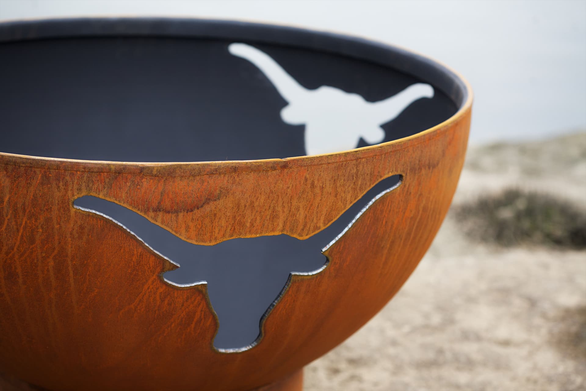 Close view of fire flickering through longhorn cutout in Long Horn 36" carbon steel fire pit by Fire Pit Art.  Made in USA.