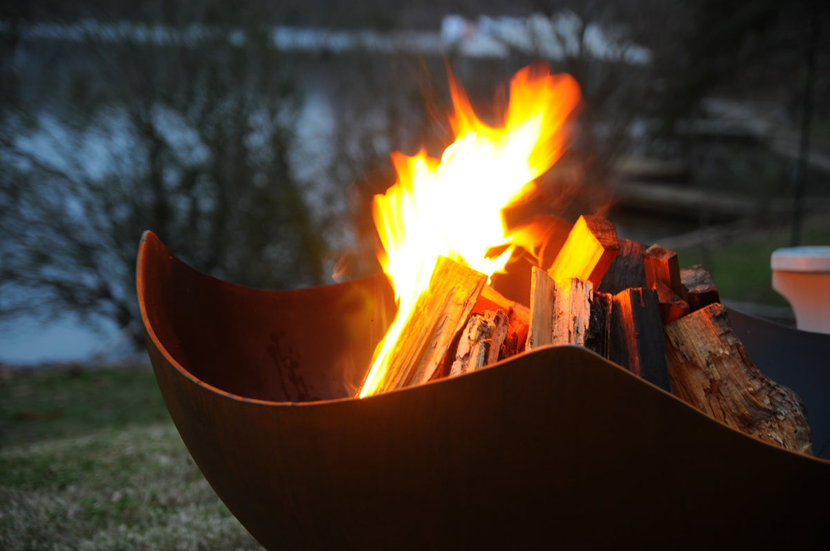 Close up of glowing wood burning in Manta Ray 36" carbon steel fire pit by Fire Pit Art.