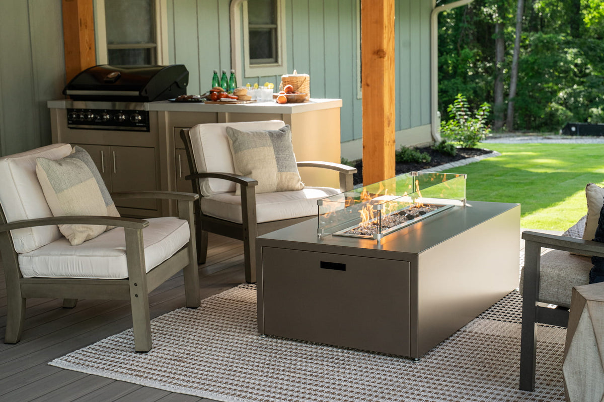 Endura Concrete finish Milan Linear propane fire table close up with chairs and summer setup (wind shield sold separately).

