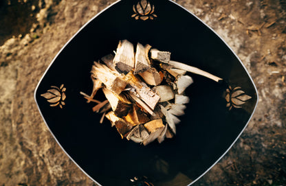 Topview of Namaste' 36" fire pit.  Has unlit wood inside with view of all four Lotus Flower cutouts.