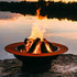 Open wood fire burning in the Saturn 41-inch carbon steel fire pit at sunset by a lake, highlighting the fire bowl’s wide celestial-inspired rim and rustic patina finish.