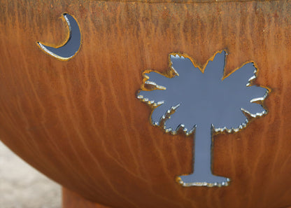 Detailed view of the crescent moon and palm tree cutouts on the Tropical Moon 36-inch carbon steel fire pit by Fire Pit Art.