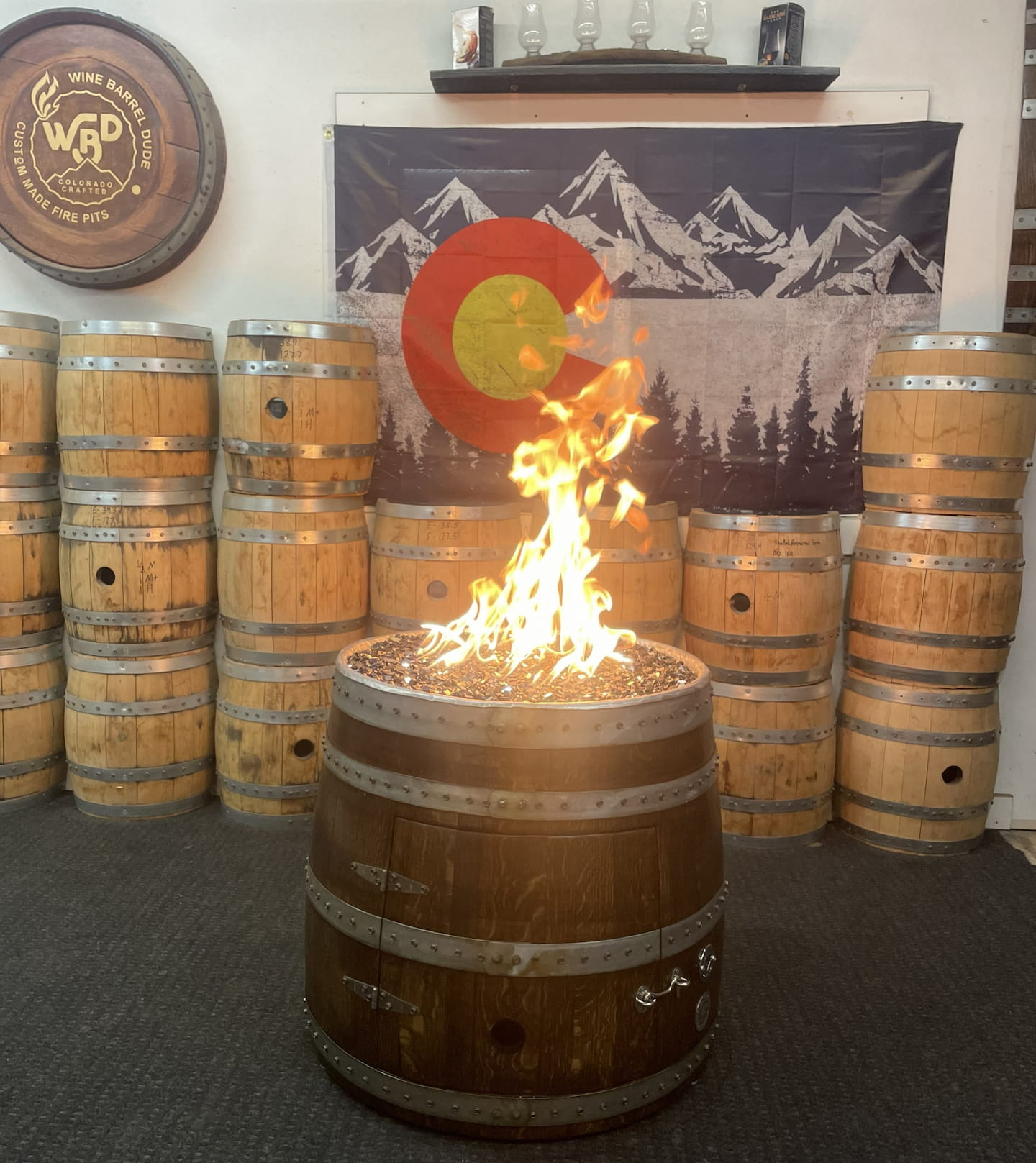 Wine barrel fire pit burning in rustic showroom setting with handcrafted wood barrel design.