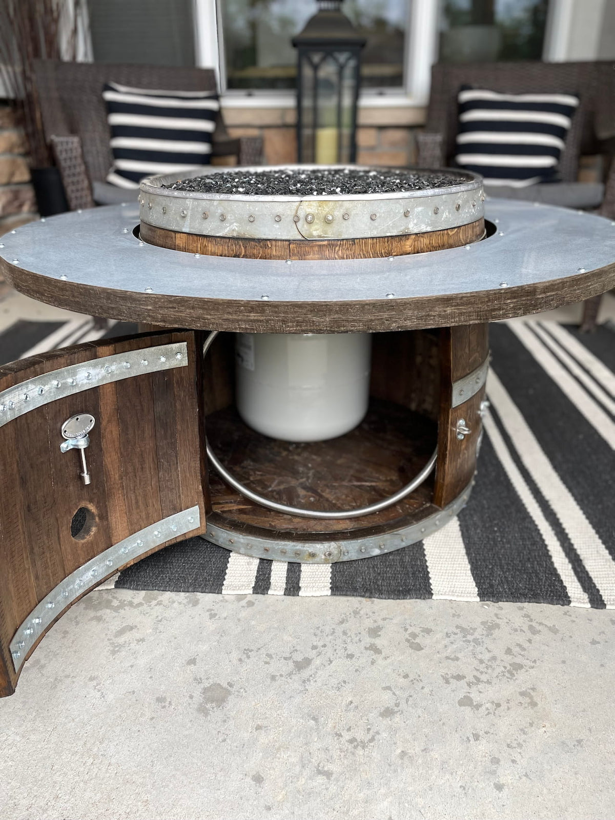 Access door open on wine barrel fire pit – showing hidden storage for propane tank inside the barrel base.  Propane tank sold separately.